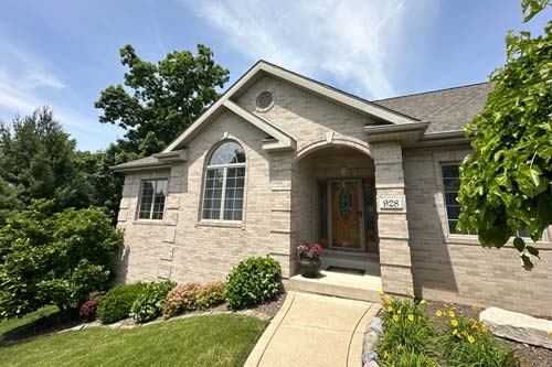 Stone siding home with a light brown wooden front door.