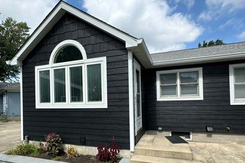 Black panel house with white fram windows.